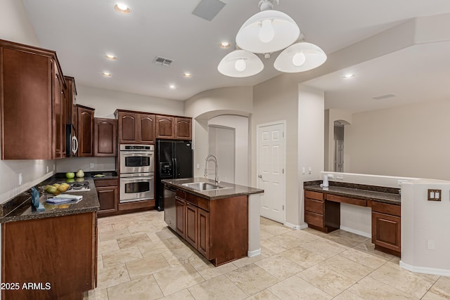 kitchen featuring appliances with stainless steel finishes, pendant lighting, sink, dark brown cabinets, and a center island with sink