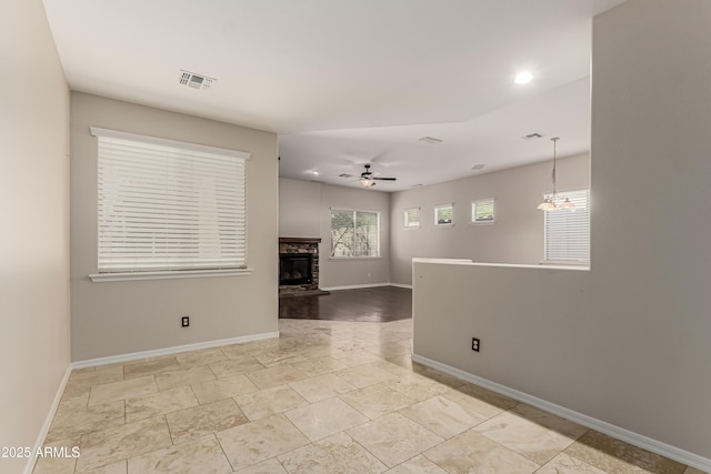 spare room with a stone fireplace and ceiling fan