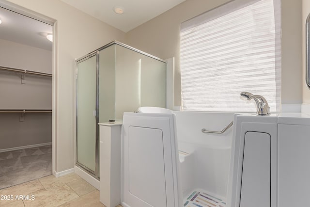 bathroom with washer / dryer, tile patterned floors, and walk in shower