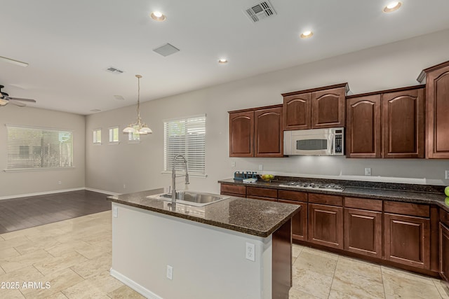 kitchen with decorative light fixtures, sink, ceiling fan, stainless steel appliances, and a center island with sink