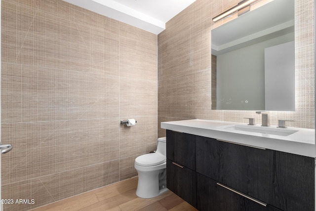 bathroom with vanity, wood-type flooring, tile walls, and toilet