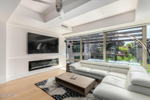 living room featuring ceiling fan, light hardwood / wood-style flooring, and a raised ceiling