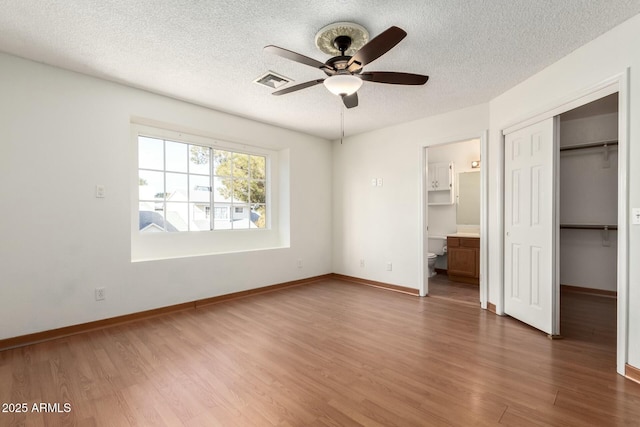 unfurnished bedroom featuring connected bathroom, a closet, ceiling fan, and dark wood-type flooring