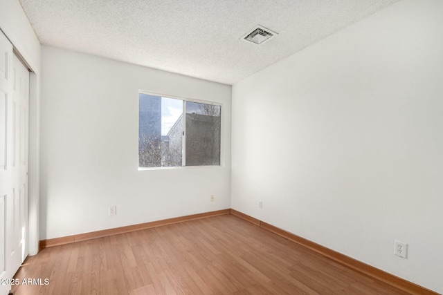 spare room featuring hardwood / wood-style flooring and a textured ceiling