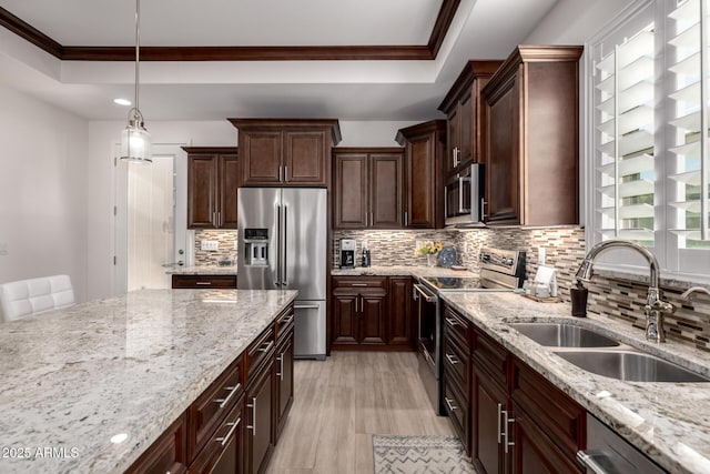 kitchen featuring sink, stainless steel appliances, decorative light fixtures, and a raised ceiling