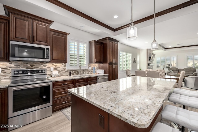 kitchen featuring stainless steel appliances, a breakfast bar, decorative light fixtures, and a tray ceiling