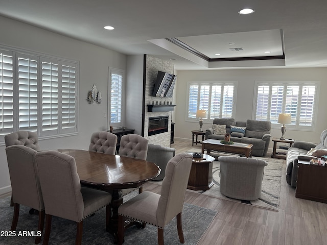 dining area with a stone fireplace and a tray ceiling