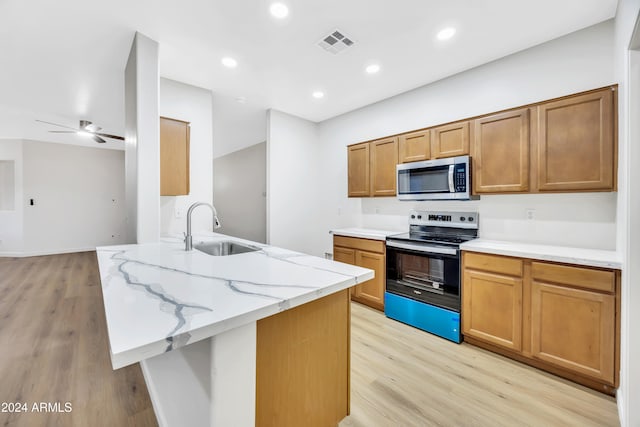 kitchen with ceiling fan, sink, stainless steel appliances, and light hardwood / wood-style flooring