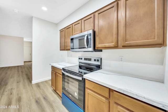 kitchen featuring light stone countertops, light wood-type flooring, and appliances with stainless steel finishes