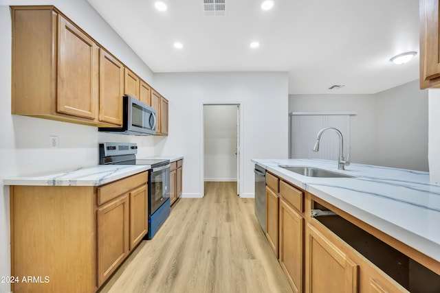 kitchen with light stone counters, stainless steel appliances, light hardwood / wood-style flooring, and sink