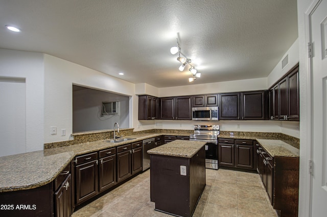 kitchen featuring rail lighting, sink, appliances with stainless steel finishes, kitchen peninsula, and a kitchen island