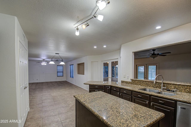 kitchen featuring dishwasher, sink, a center island, light stone counters, and dark brown cabinetry