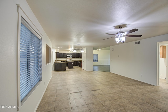 unfurnished living room featuring light tile patterned flooring, a textured ceiling, and ceiling fan