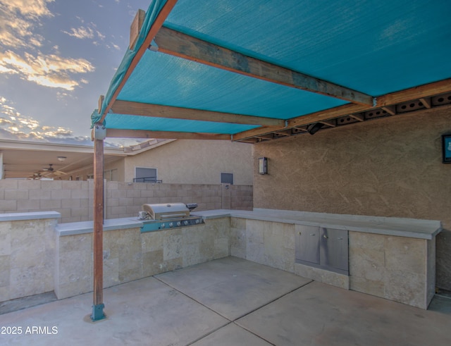 patio terrace at dusk with a grill and an outdoor kitchen