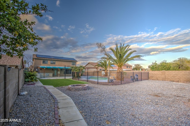 yard at dusk featuring a fenced in pool, a patio, and an outdoor fire pit