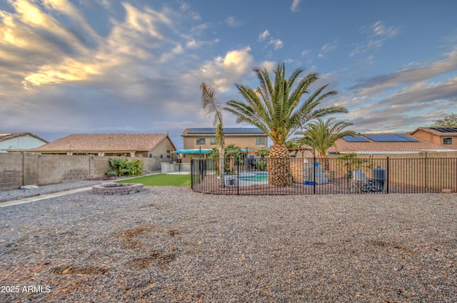 yard at dusk with a fenced in pool, a patio area, and an outdoor fire pit