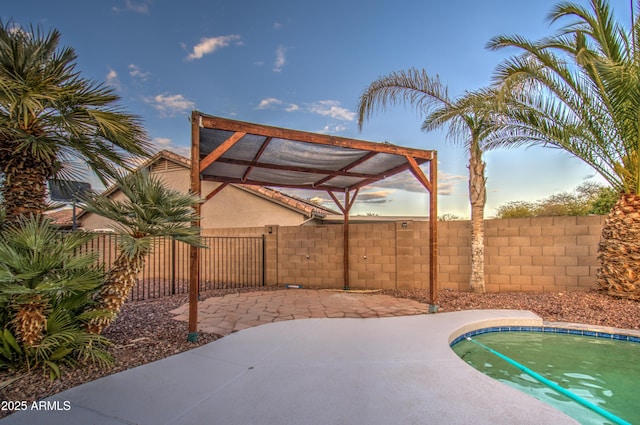 patio terrace at dusk with a fenced in pool