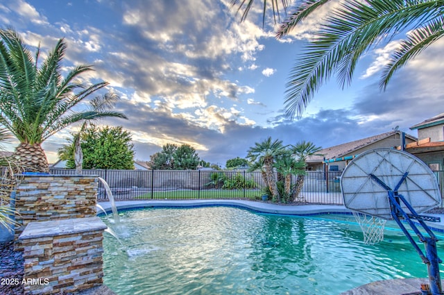 pool at dusk featuring pool water feature