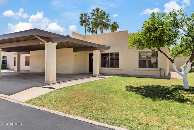 exterior space featuring driveway, a lawn, a carport, and stucco siding