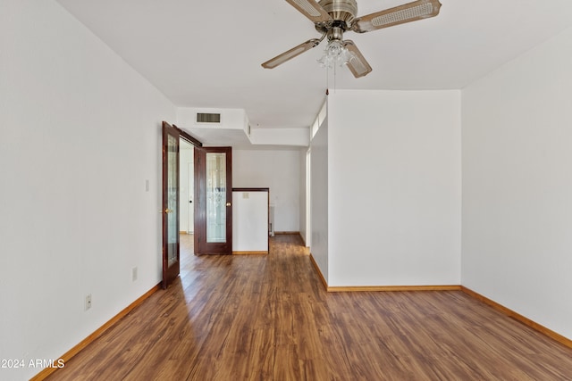 empty room with wood finished floors, visible vents, and baseboards