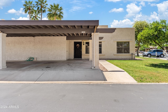 view of front facade featuring covered parking, a front lawn, and stucco siding