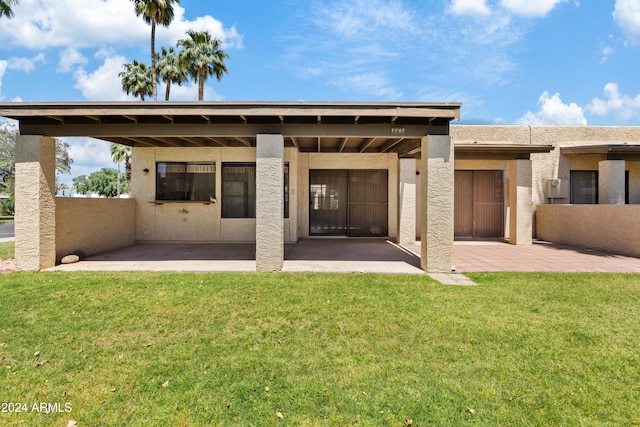 rear view of property with a patio, a lawn, and stucco siding