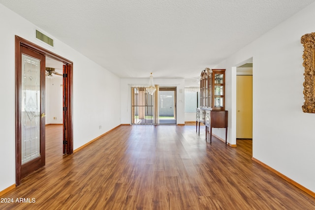 empty room with a textured ceiling, wood finished floors, and visible vents