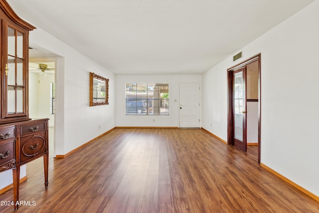 unfurnished room with visible vents, a textured ceiling, baseboards, and wood finished floors