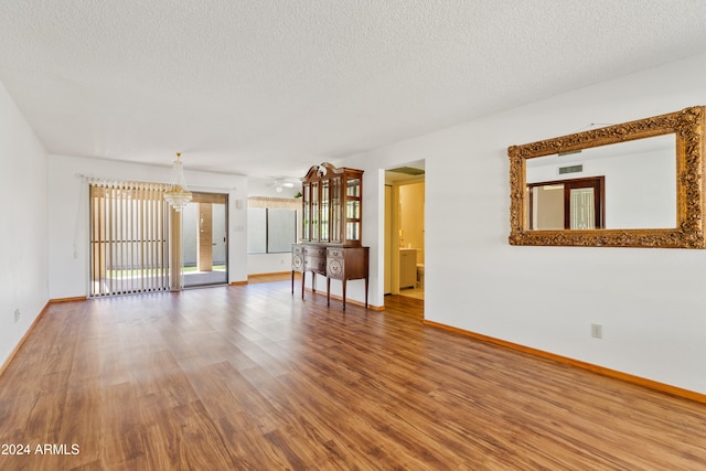 empty room with a textured ceiling, wood finished floors, and visible vents