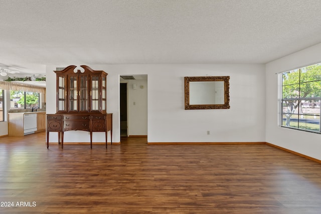 unfurnished room with a textured ceiling, baseboards, and wood finished floors