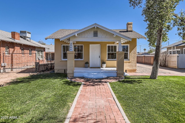 bungalow with a chimney, roof with shingles, fence, a front yard, and stucco siding