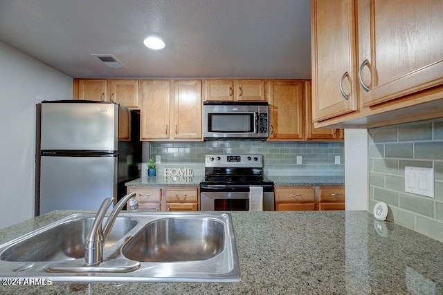 kitchen featuring tasteful backsplash, stainless steel appliances, sink, and light stone counters