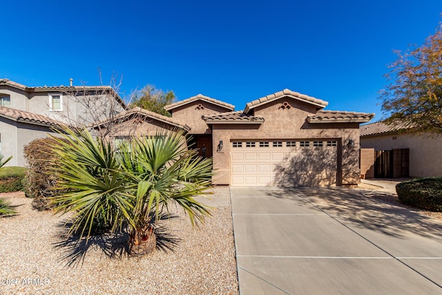 mediterranean / spanish home featuring a garage, a tiled roof, concrete driveway, and stucco siding