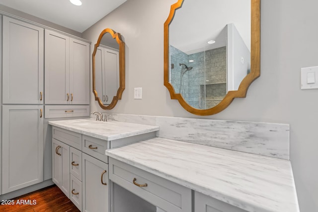 bathroom featuring tiled shower, vanity, wood finished floors, and recessed lighting