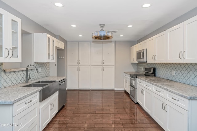 kitchen with glass insert cabinets, white cabinetry, recessed lighting, a sink, and stainless steel appliances