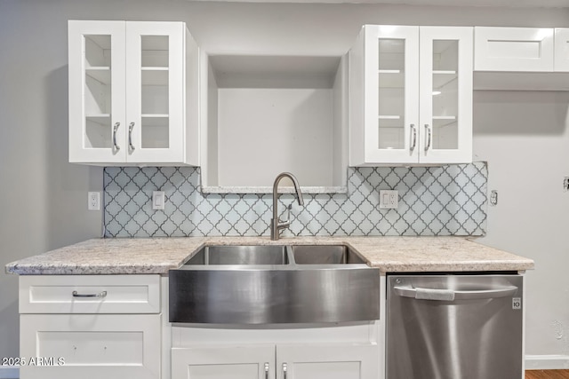 kitchen with decorative backsplash, stainless steel dishwasher, a sink, and white cabinets