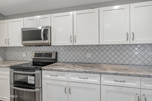 kitchen with backsplash, white cabinets, appliances with stainless steel finishes, and light stone countertops