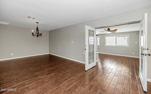 unfurnished room with dark wood-type flooring, visible vents, baseboards, and ceiling fan with notable chandelier