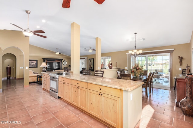 kitchen featuring light brown cabinets, ceiling fan with notable chandelier, vaulted ceiling, and stainless steel range oven