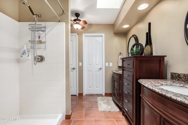 bathroom with a tile shower, vanity, ceiling fan, and tile patterned floors