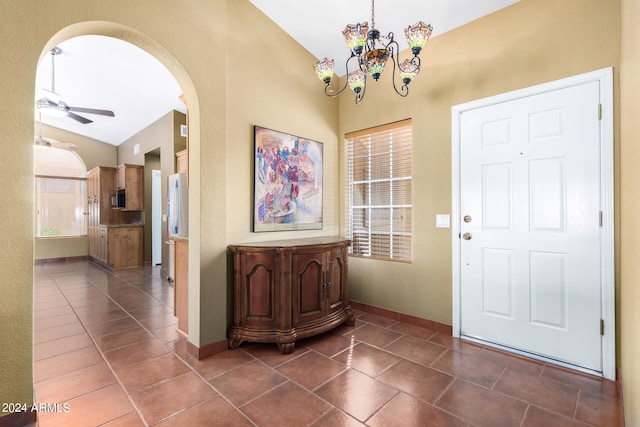 entrance foyer featuring dark tile patterned flooring, ceiling fan with notable chandelier, and lofted ceiling