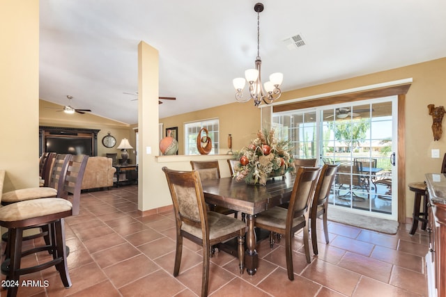 dining space featuring ceiling fan with notable chandelier, lofted ceiling, and dark tile patterned floors