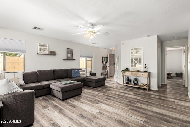 living room featuring visible vents, a ceiling fan, and wood finished floors