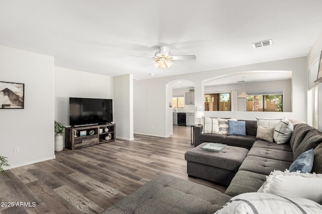 living room with visible vents, a ceiling fan, wood finished floors, arched walkways, and baseboards