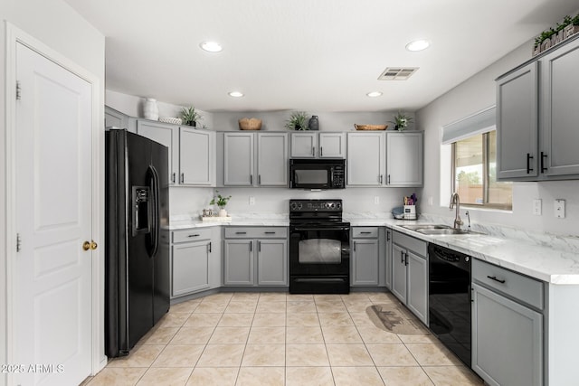 kitchen with visible vents, black appliances, gray cabinets, a sink, and light tile patterned floors