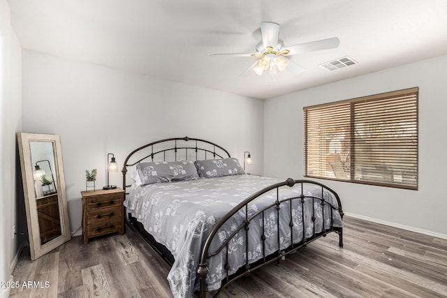 bedroom with a ceiling fan, wood finished floors, visible vents, and baseboards