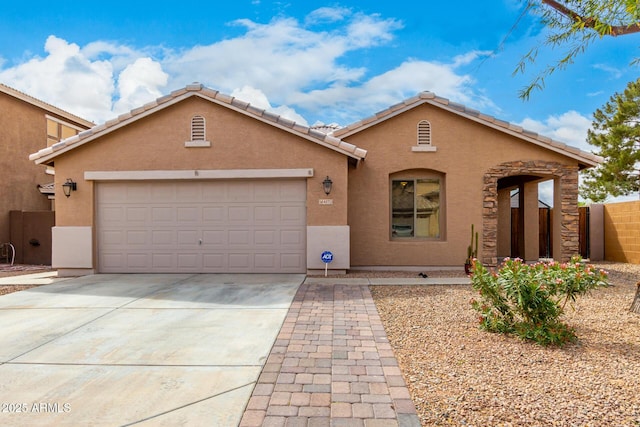 view of front of home with fence, a tiled roof, stucco siding, driveway, and an attached garage