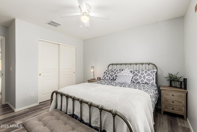 bedroom with wood finished floors, visible vents, a closet, and baseboards