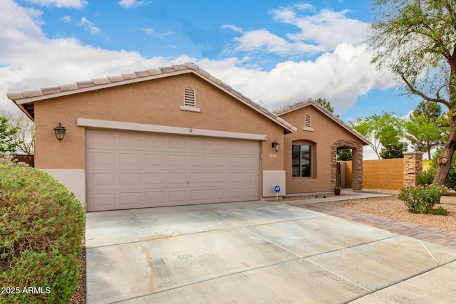 view of front of home featuring stucco siding, a garage, concrete driveway, and fence