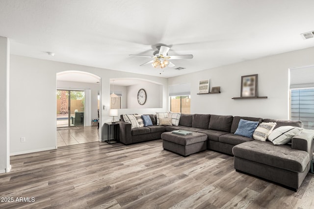 living area with visible vents, a ceiling fan, and wood finished floors